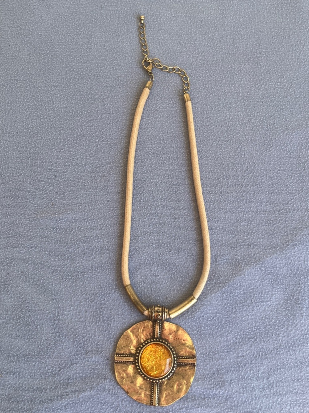 Gold Tone hammered medallion pendant featuring a yellow glass cabochon stone
